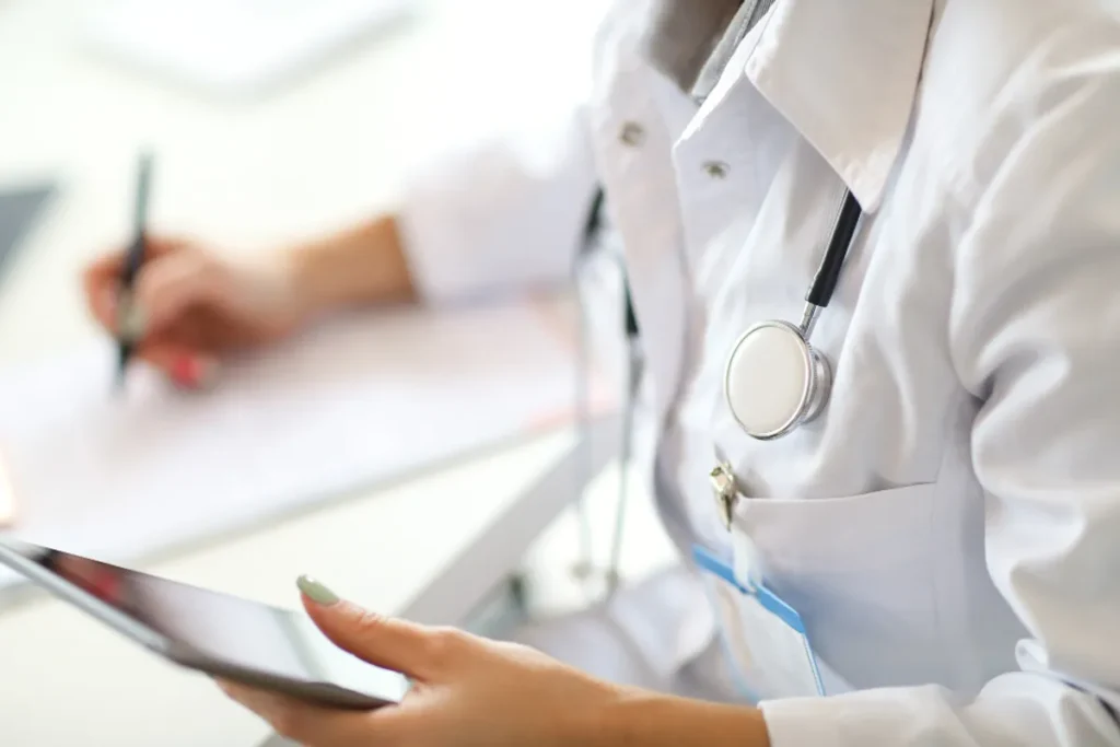 Médico analisando dados de inteligência artificial em um tablet em consultório médico.